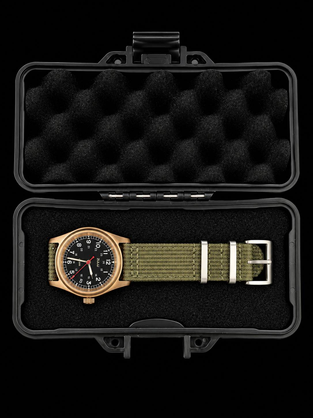 A wristwatch with a black dial, olive green NATO-style fabric strap, and rose gold case, displayed inside an open black hard case with black foam padding on a black background.