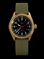 A wristwatch with a bronze-toned metal case, a black dial featuring white Arabic numerals and a red second hand, and an olive green woven fabric strap, shown against a solid black background.